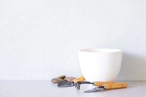 White ceramic pots with planters, peat, stones, on the tabletop and white wall background. photo