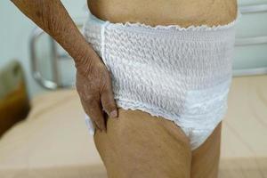 Asian elder senior woman patient wearing adult incontinence diaper pad in hospital. photo