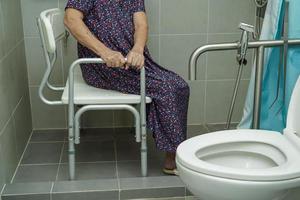 Asian elderly old woman patient use toilet support rail in bathroom, handrail safety grab bar, security in nursing hospital. photo