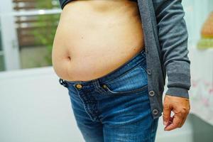 la mujer asiática muestra un vientre gordo de gran tamaño con sobrepeso y obesidad en la oficina. foto