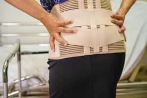 Asian lady patient wearing back pain support belt for orthopedic lumbar with walker. photo