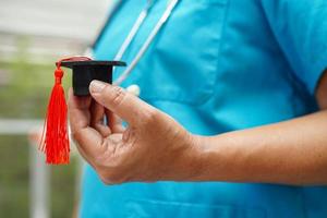 Asian woman doctor holding graduation hat in hospital, Medical education concept. photo