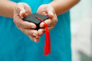 Asian woman doctor holding graduation hat in hospital, Medical education concept. photo