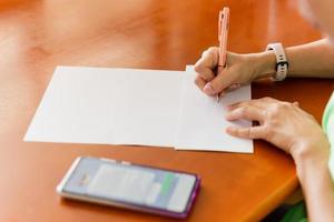 Woman with pen writing address on envelope. photo