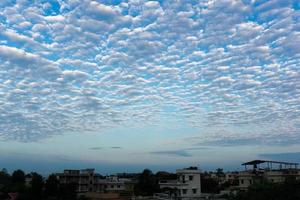 25th july 2020. dehradun,uttarakhand, India. Different shapes of white clouds forming on the blue skies with residential housing and buildings. photo