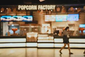 Movie theater entrance interior blur image use for background of business and cinema concept. Abstract blur people queuing to buy ticket at the counter and buy popcorn. photo