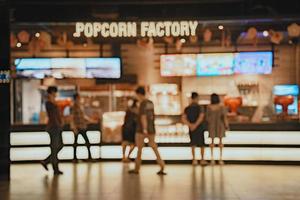 Movie theater entrance interior blur image use for background of business and cinema concept. Abstract blur people queuing to buy ticket at the counter and buy popcorn. photo