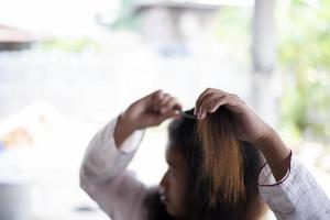 retrato de una chica triste con el pelo largo que tiene un problema con las puntas y ambas manos sujetan las puntas del pelo. concepto perfecto. foto