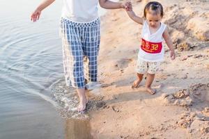 A young mother plays with her 2-5 year old daughter on the beach in summer. Outdoor resort on the lake Have a good rest on weekends, family days. photo