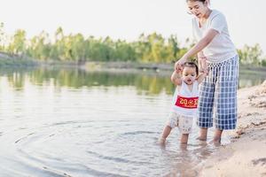 A young mother plays with her 2-5 year old daughter on the beach in summer. Outdoor resort on the lake Have a good rest on weekends, family days. photo