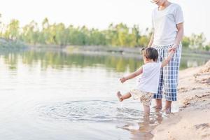 A young mother plays with her 2-5 year old daughter on the beach in summer. Outdoor resort on the lake Have a good rest on weekends, family days. photo