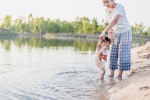 A young mother plays with her 2-5 year old daughter on the beach in summer. Outdoor resort on the lake Have a good rest on weekends, family days. photo