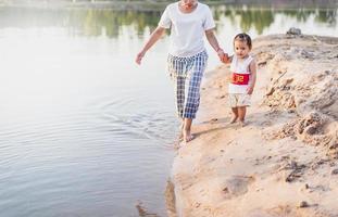 A young mother plays with her 2-5 year old daughter on the beach in summer. Outdoor resort on the lake Have a good rest on weekends, family days. photo