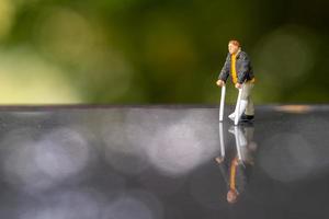 Miniature people man with broken leg is using crutch For Walking photo