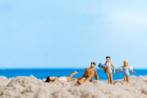 Miniature people Happy family relaxing on The beach photo