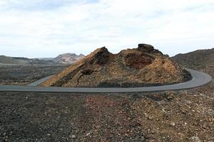 Landscape of a vast lava field. The road was made with solidified lava. Lanzarote, Canary Islands, Spain photo