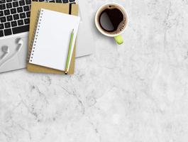 Top view blank notebook,white earphone,pencil,cup of coffee on white marble photo