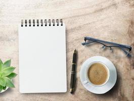 Blank notepad,glasses, pen and coffee cup on office desk background. photo