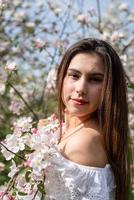 joven mujer caucásica disfrutando del florecimiento de un manzano foto