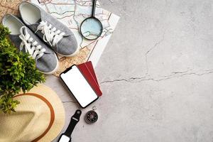 Top view travel accessories with shoes, map, smartphone with mockup screen, hat. Tourist essentials. photo