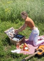 young caucasian woman preparing picnic basket outdoors, ready to have a picnic photo
