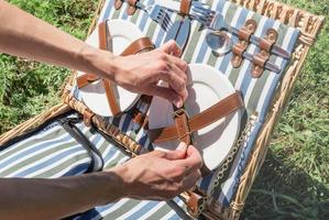 young caucasian woman hand preparing picnic basket outdoors, ready to have a picnic photo