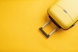 Top view yellow travel bag or suitcase on solid yellow background copy space. Tourist essentials photo