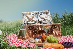 Closeup of picnic basket with drinks and food on the grass photo