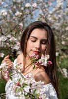 joven mujer caucásica disfrutando del florecimiento de un manzano foto