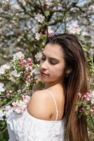 Young caucasian woman enjoying the flowering of an apple trees photo