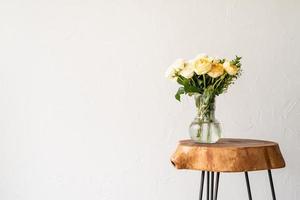minimal home interior with stylish wooden coffee table and bouquet of fresh roses photo