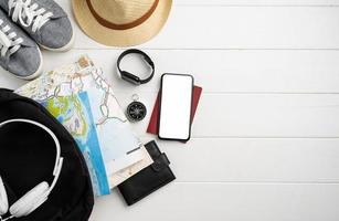 Top view travel accessories with shoes, map, smartphone with mockup screen, hat. Tourist essentials. photo