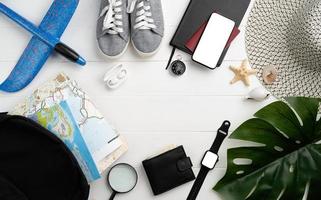 Top view travel accessories with shoes, map, smartphone with mockup screen, hat. Tourist essentials. photo