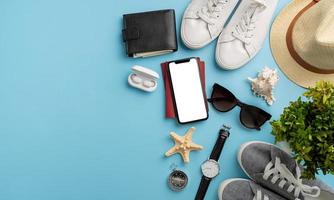 Top view travel accessories with shoes, map, smartphone with mockup screen, hat. Tourist essentials. photo