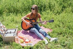 Young woman playing guitar on a picnic photo