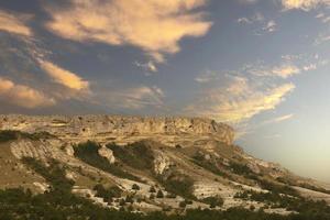 Mountain canyon in the dry season against the backdrop of sunset and pink clouds. White Rock, Crimea. photo