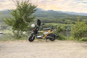 Crimea, Ukraine, July 23, 2021 - A motorcycle, a yellow scooter against the backdrop of a sunset in the Crimean mountains and a lake. Lifestyle. photo