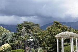 cenador de té en el fondo de montañas con nubes entre los árboles en el parque de la ciudad. foto