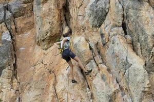 chica extrema, escaladora en una roca pura gris-roja en las montañas de Crimea. foto