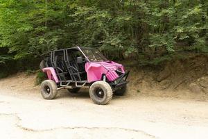 Crimea, Ukraine, July 24, 2021 - Pink off-road car, SUV, buggy against the background of green trees. Lifestyle. photo