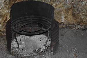 Extinguished bonfire ashes in a safety structure placed in front of a rock wall photo