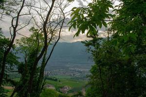 Landscape of rural village with mountains in the background, enclosed in a frame of trees photo