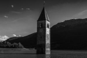 campanario sumergido de curon venosta en italia tirol del sur, antiguo edificio de un antiguo pueblo tragado por el agua del lago resia foto