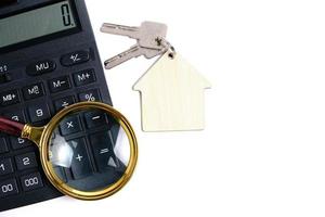 calculadora, lupa y llaves de la casa. concepto de compra y venta de viviendas, hipotecas y alquiler de una casa o apartamento. foto