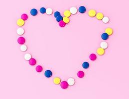 Colorful chocolate button candy chocolate coated beans Heart shaped on pink Background valentine Birthday anniversary wedding love concept photo