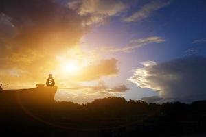 silhouette money bag Icon on the stone in the mountain with a calm orange sunset sky. photo