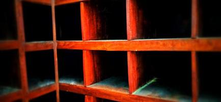 An old and dull red orange wooden locker under a dim background. photo