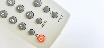 An isolated gray television remote control on the white gray background. Suitable for business, promotion, poster, backdrop, and advertising of company and industry. photo