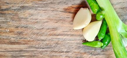 Vegetables of leek, garlic, and green chilli on the wooden cutting board. Vegetables ingredient background design. Suitable for advertising of food, drink, poster, backdrop, food company and industry. photo
