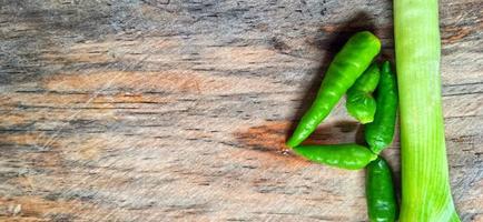 Vegetables of leek, garlic, and green chilli on the wooden cutting board. Vegetables ingredient background design. Suitable for advertising of food, drink, poster, backdrop, food company and industry. photo